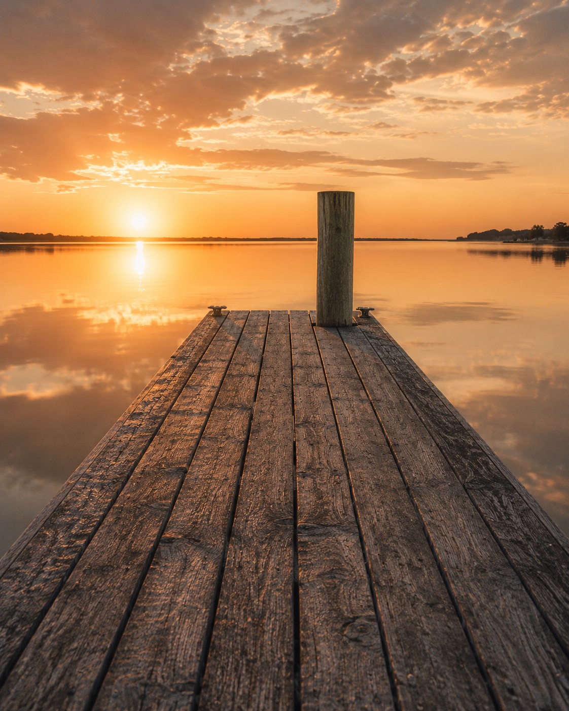 A dock running out to glassy water at sunset